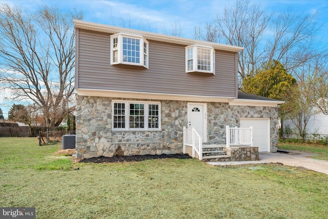 colonial-style house featuring a front lawn, fence, concrete driveway, stone siding, and an attached garage