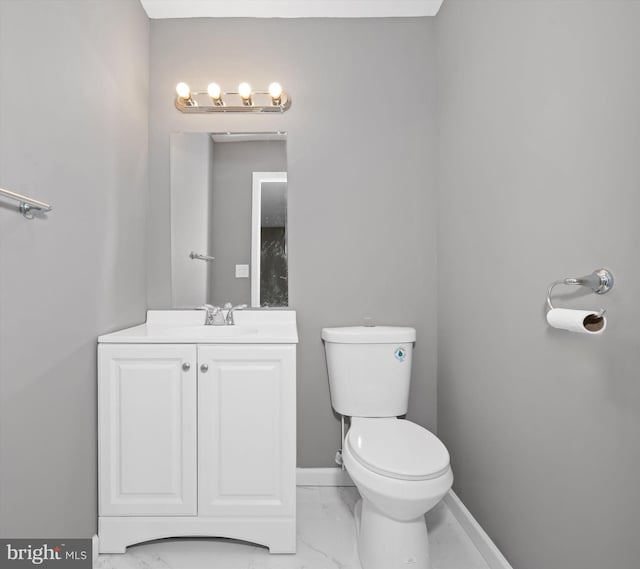 half bath with baseboards, toilet, marble finish floor, and vanity