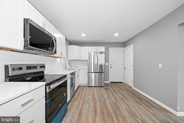 kitchen with baseboards, decorative backsplash, appliances with stainless steel finishes, white cabinetry, and a sink