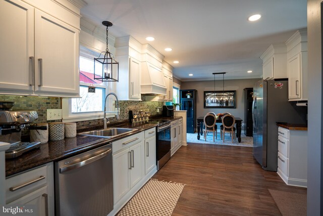 kitchen with dark wood-style floors, an inviting chandelier, a sink, decorative backsplash, and stainless steel appliances