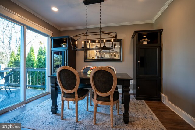 dining room featuring visible vents, crown molding, baseboards, an inviting chandelier, and wood finished floors