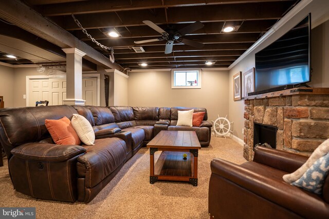 carpeted living area with a stone fireplace, baseboards, and ceiling fan