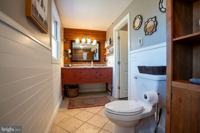 bathroom featuring wooden walls, toilet, and vanity