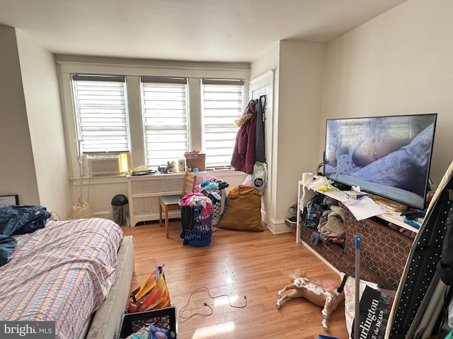 bedroom with radiator, wood finished floors, baseboards, and cooling unit