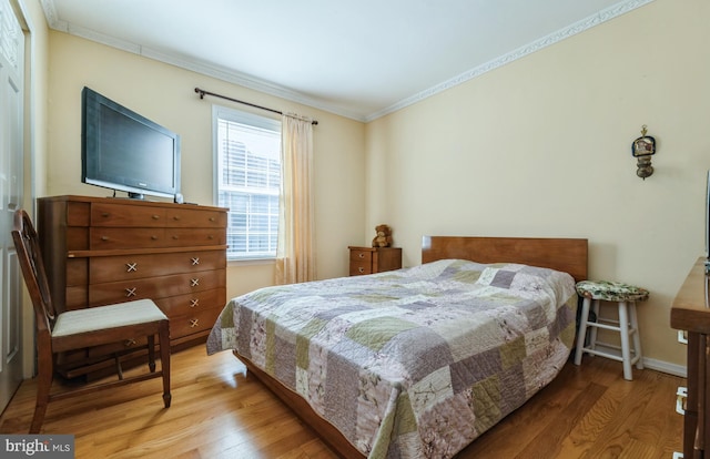 bedroom with wood finished floors, baseboards, and ornamental molding