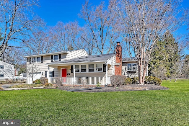 tri-level home with a chimney, covered porch, and a front yard