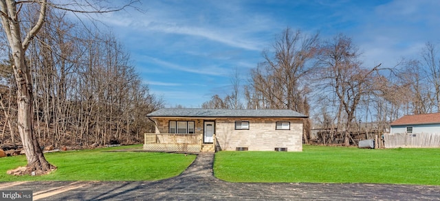 view of front facade with stone siding, covered porch, a front lawn, and fence