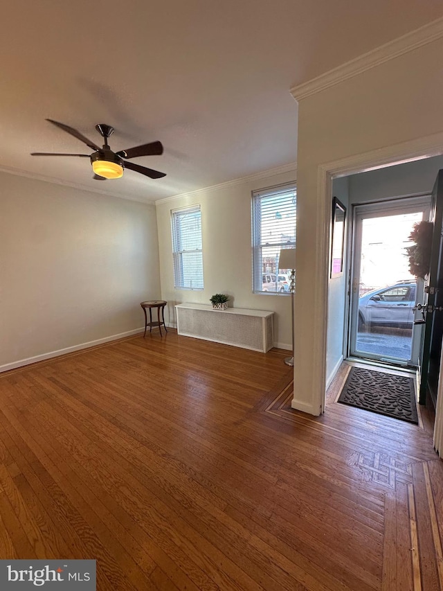 empty room featuring ceiling fan, baseboards, wood finished floors, and ornamental molding