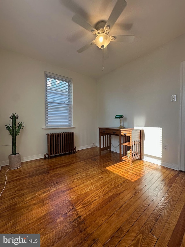 unfurnished room with hardwood / wood-style flooring, radiator heating unit, and baseboards