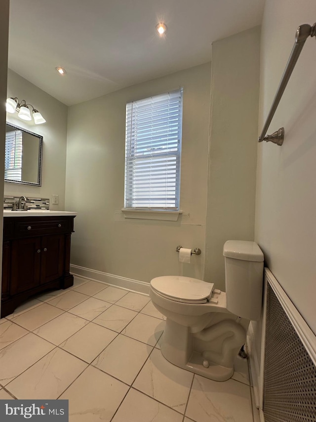 half bath with vanity, toilet, recessed lighting, and baseboards