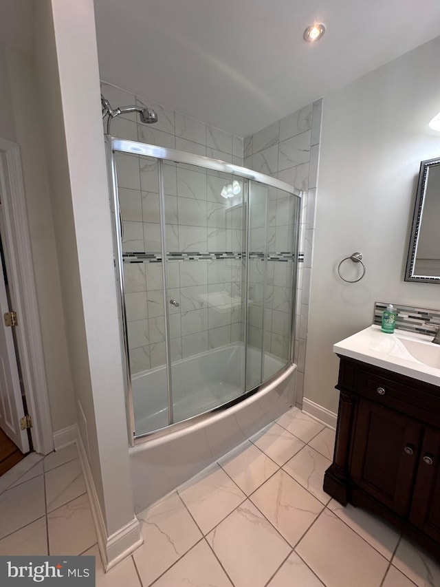 full bathroom with baseboards, shower / bath combination with glass door, marble finish floor, and vanity