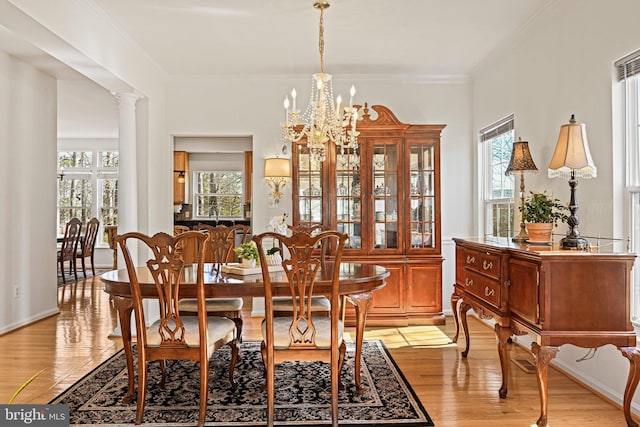 dining area with a notable chandelier, crown molding, and light wood-type flooring