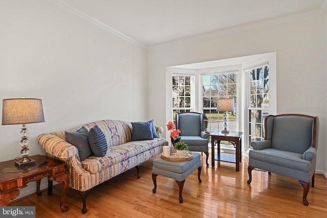 living room featuring baseboards, ornamental molding, and light wood finished floors