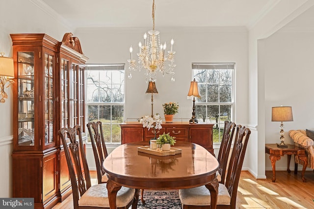 dining space with a chandelier, baseboards, light wood-style flooring, and crown molding