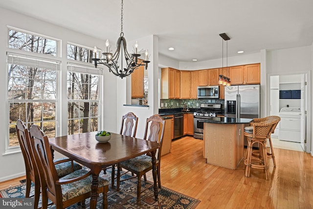 dining room featuring light wood finished floors, a notable chandelier, recessed lighting, and washer / clothes dryer