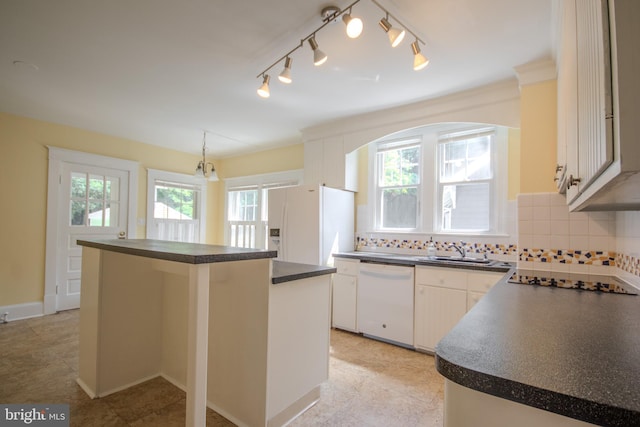 kitchen featuring white appliances, a kitchen island, a sink, dark countertops, and backsplash