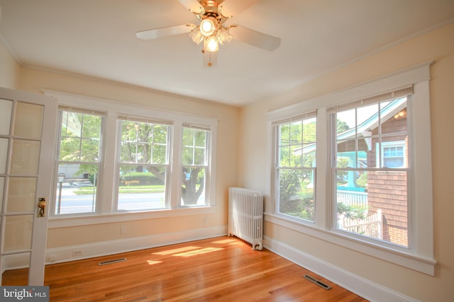 spare room featuring visible vents, radiator, baseboards, and wood finished floors