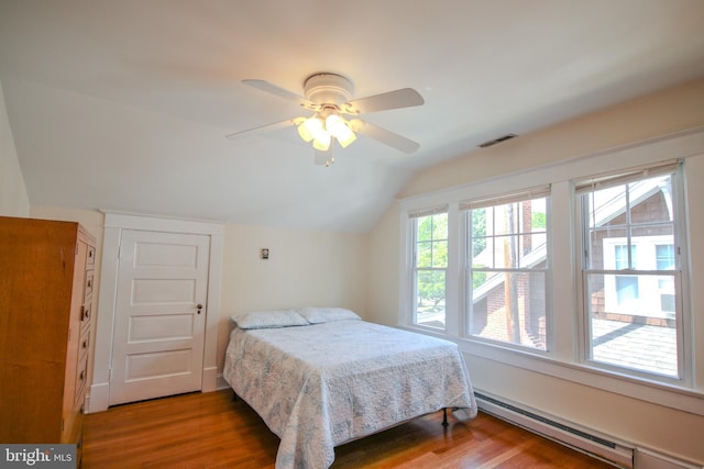 bedroom featuring visible vents, a baseboard heating unit, vaulted ceiling, wood finished floors, and a ceiling fan