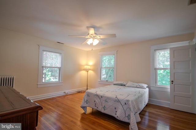 bedroom featuring visible vents, a ceiling fan, baseboards, and wood finished floors