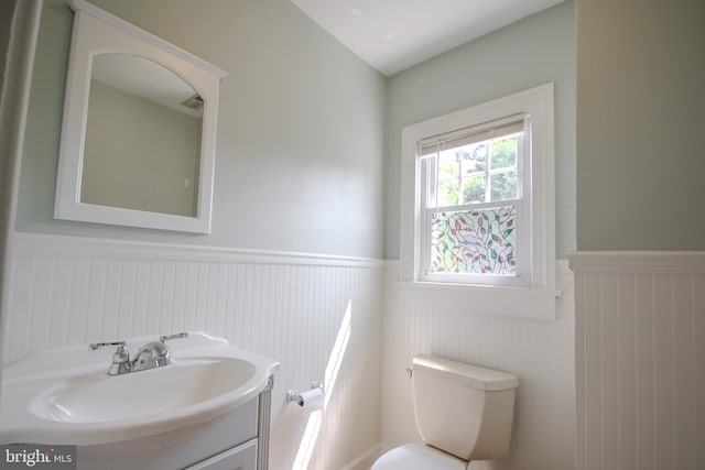 bathroom featuring a wainscoted wall, toilet, and vanity