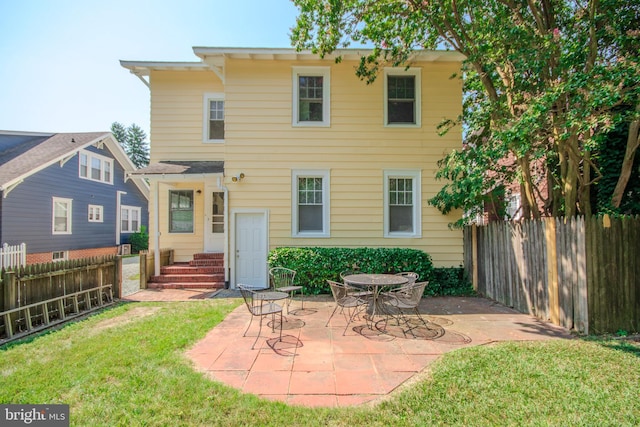 rear view of house with entry steps, a patio, a yard, and a fenced backyard