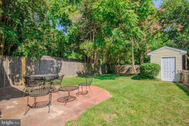 view of yard with an outbuilding, outdoor dining area, a fenced backyard, a storage shed, and a patio area