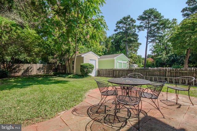 view of patio / terrace with an outbuilding, outdoor dining area, and a fenced backyard