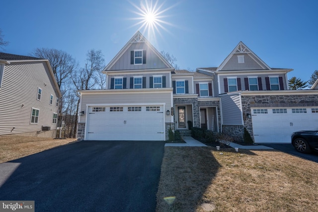 view of front of home featuring board and batten siding, aphalt driveway, an attached garage, and stone siding