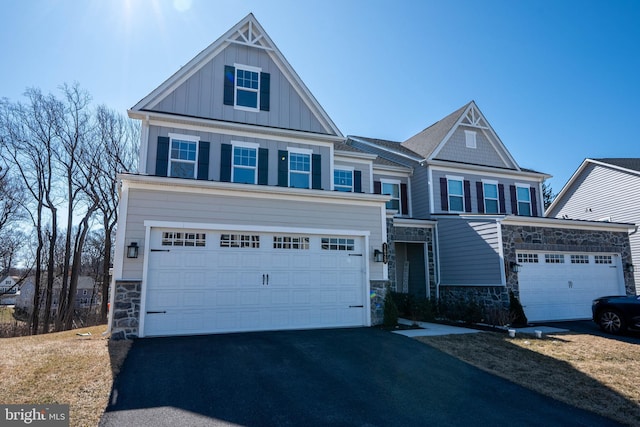 view of front facade featuring aphalt driveway, stone siding, board and batten siding, and an attached garage