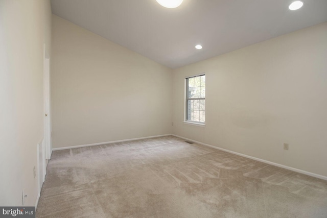 unfurnished room with light carpet, baseboards, and vaulted ceiling