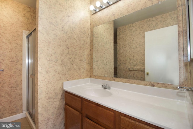 full bathroom with vanity, a shower stall, and wallpapered walls