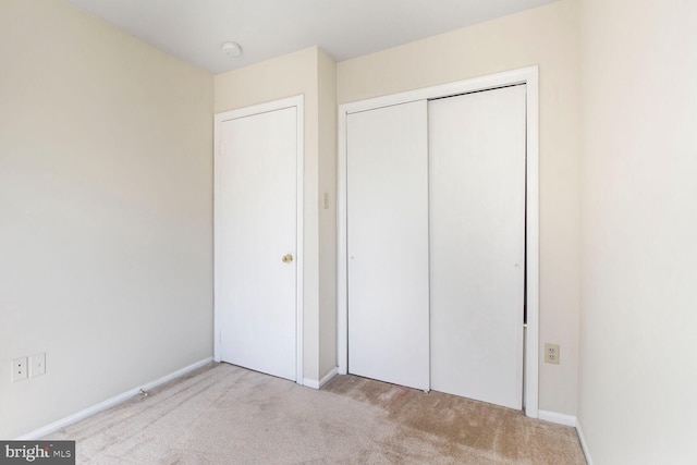 unfurnished bedroom with a closet, baseboards, and carpet