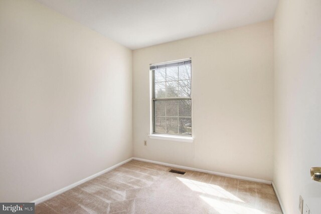 carpeted spare room featuring visible vents and baseboards