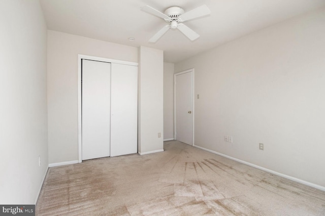 unfurnished bedroom with carpet flooring, a ceiling fan, a closet, and baseboards