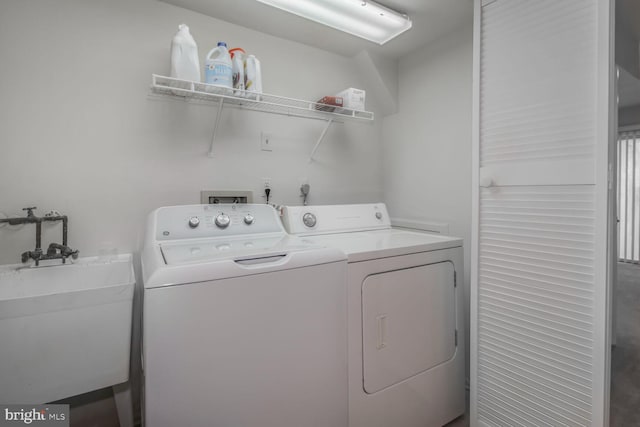 washroom featuring laundry area, separate washer and dryer, and a sink