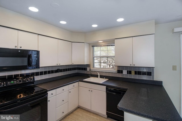 kitchen featuring black appliances, a sink, dark countertops, tasteful backsplash, and white cabinets