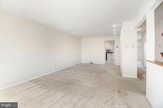 unfurnished living room featuring light carpet, recessed lighting, and baseboards