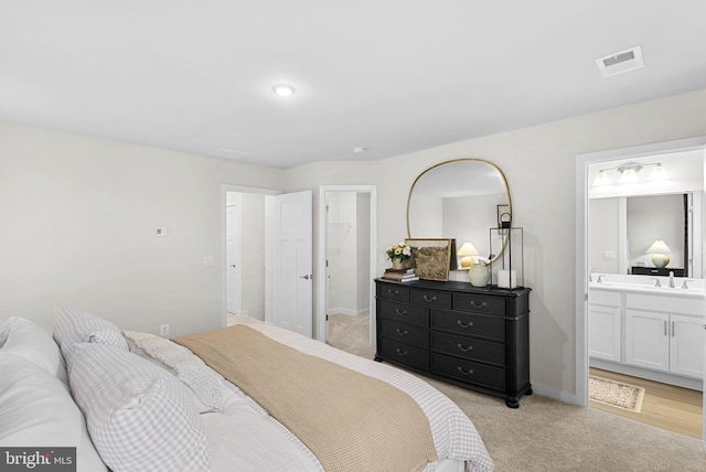 bedroom with visible vents, a sink, connected bathroom, baseboards, and light colored carpet