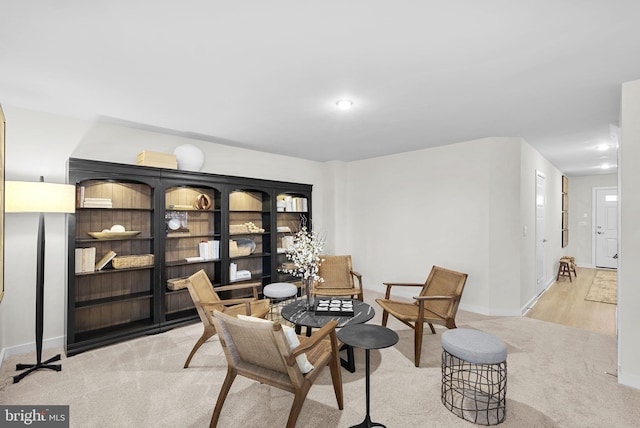 living area featuring light carpet and baseboards