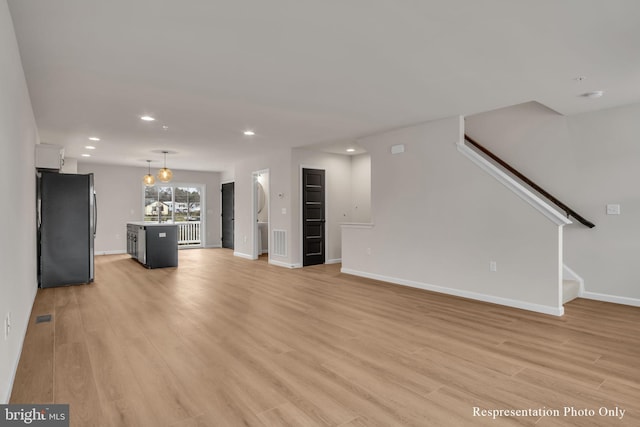 unfurnished living room with visible vents, light wood-style flooring, and stairs