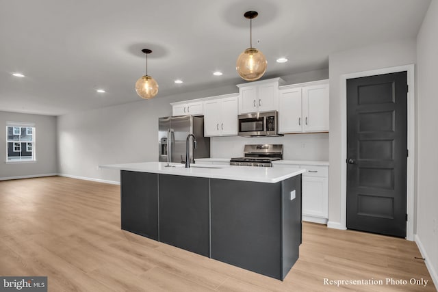 kitchen featuring a kitchen island with sink, light countertops, white cabinets, stainless steel appliances, and a sink