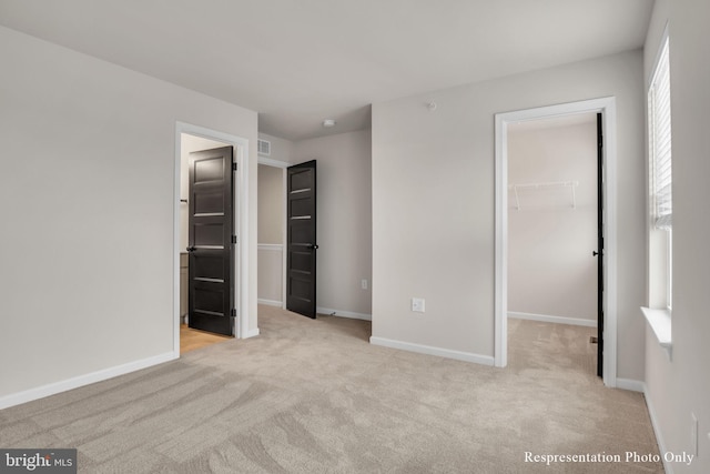 unfurnished bedroom featuring a walk in closet, carpet flooring, baseboards, and a closet