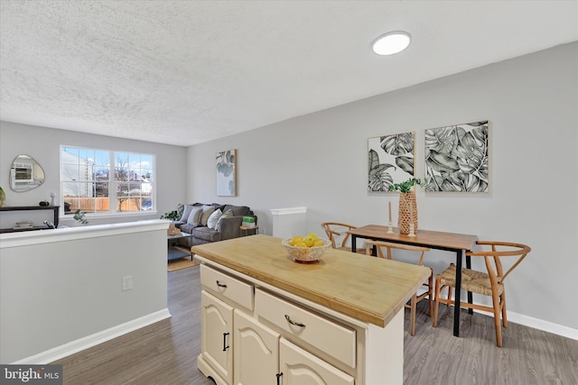 kitchen featuring baseboards, light wood-style floors, open floor plan, and a textured ceiling