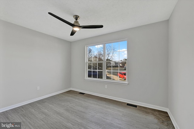 spare room with visible vents, wood finished floors, baseboards, and ceiling fan