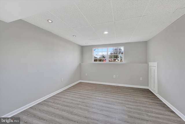 spare room featuring wood finished floors, baseboards, and a paneled ceiling