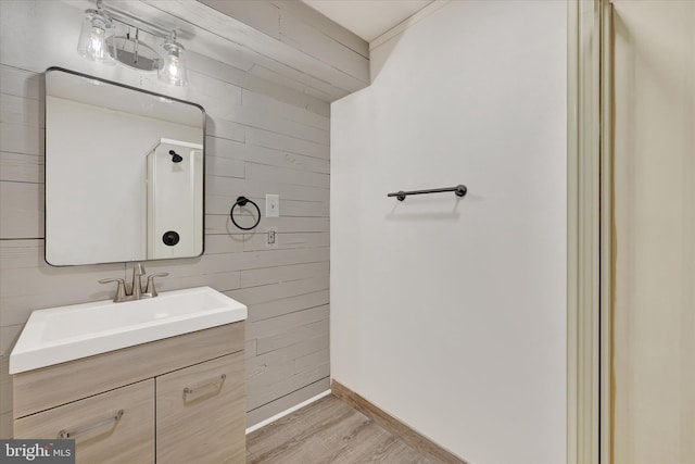 bathroom featuring wood walls, vanity, baseboards, and wood finished floors