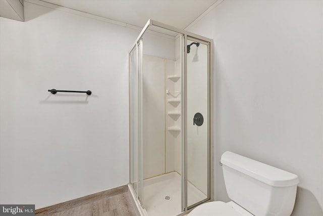 bathroom featuring wood finished floors, toilet, and a stall shower