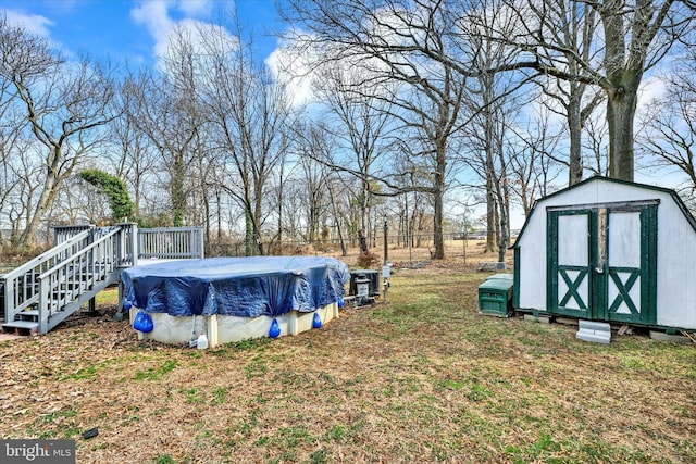 view of yard featuring a covered pool, fence, a shed, a deck, and an outdoor structure