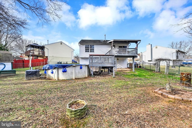 back of property with a deck, a fenced in pool, fence, and a lawn