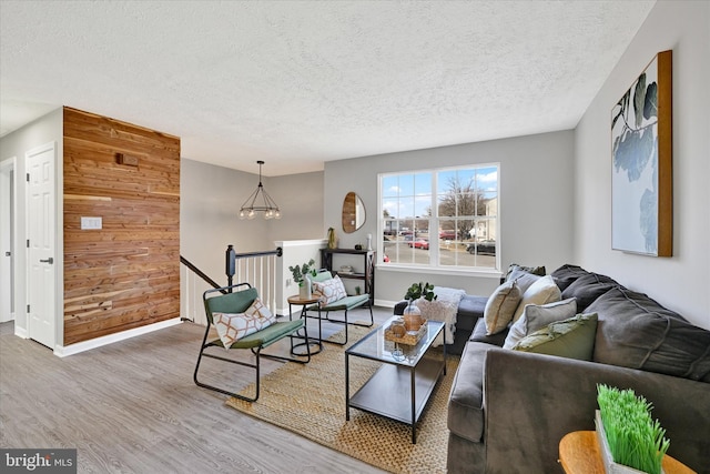 living area with wood walls, a textured ceiling, baseboards, and wood finished floors